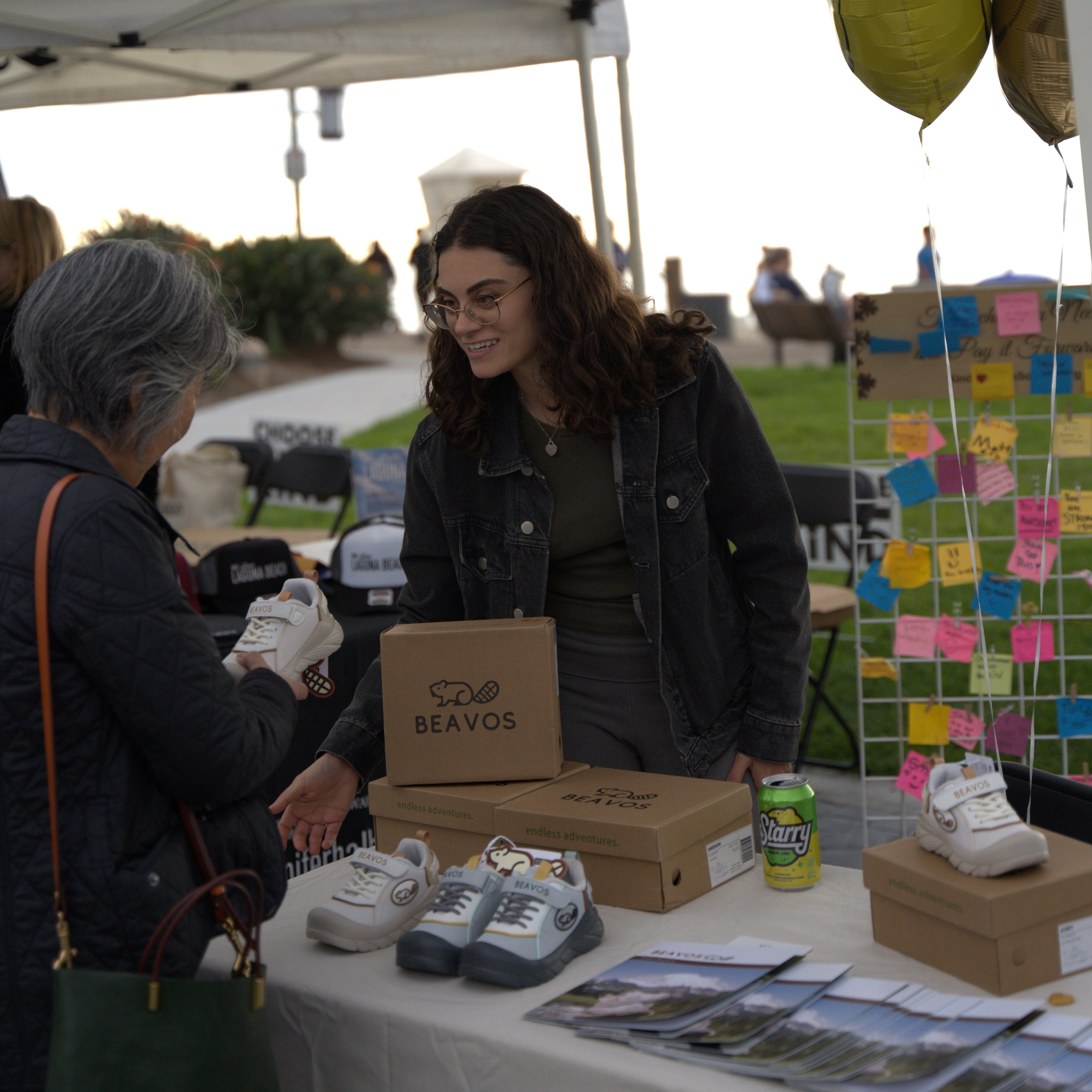 Woman interacting with a product at an outdoor event under a white tent.